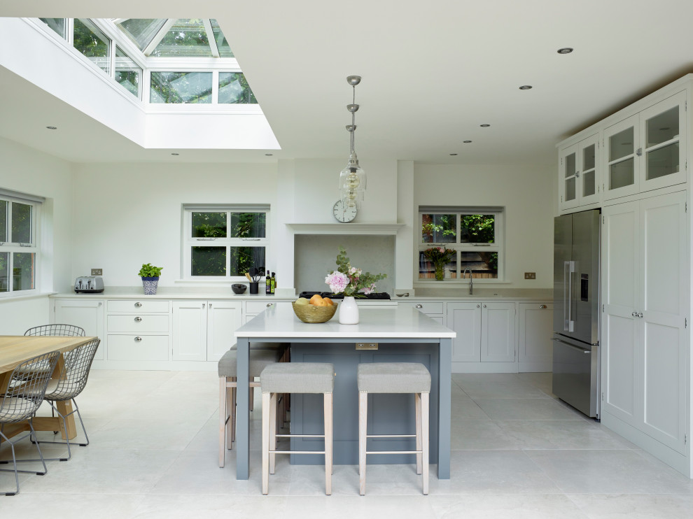 Inspiration for a large contemporary l-shaped open plan kitchen in Hertfordshire with a drop-in sink, shaker cabinets, grey cabinets, quartzite benchtops, white splashback, stone slab splashback, stainless steel appliances, porcelain floors, with island, white floor and white benchtop.