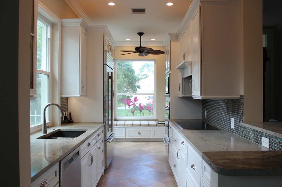 Enclosed kitchen - mid-sized transitional galley limestone floor and beige floor enclosed kitchen idea in Miami with a double-bowl sink, raised-panel cabinets, white cabinets, blue backsplash, mosaic tile backsplash, stainless steel appliances and no island