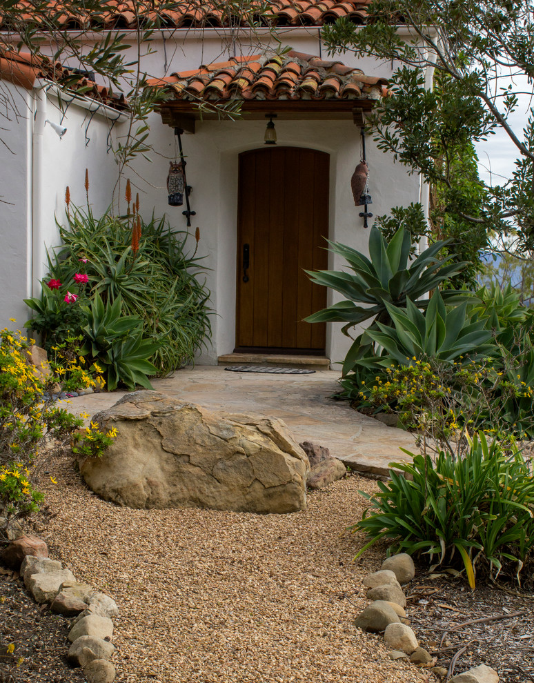 This is an example of a mid-sized side yard partial sun formal garden for summer in Santa Barbara with a garden path and gravel.