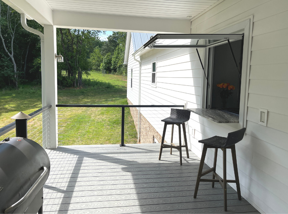 Diseño de terraza campestre en patio trasero y anexo de casas con cocina exterior y barandilla de cable