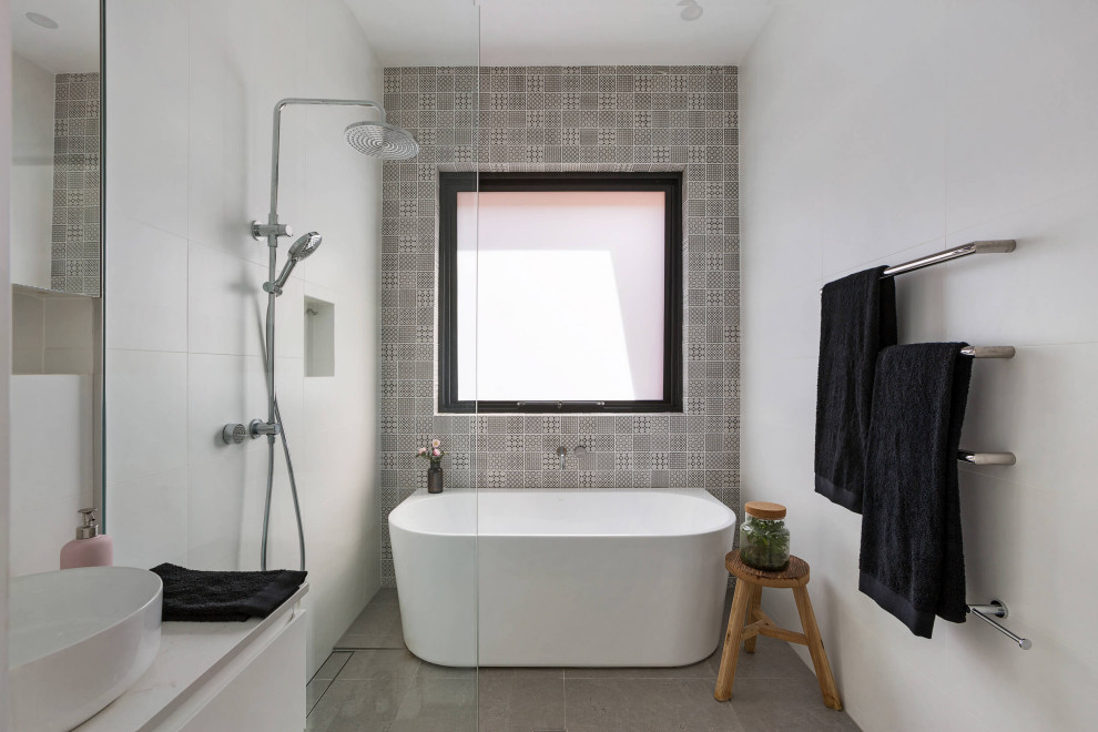 Photo of a mid-sized contemporary 3/4 bathroom in Sydney with raised-panel cabinets, white cabinets, a freestanding tub, an open shower, a one-piece toilet, black and white tile, ceramic tile, white walls, cement tiles, a vessel sink, engineered quartz benchtops, grey floor, a hinged shower door, white benchtops, a single vanity and a freestanding vanity.
