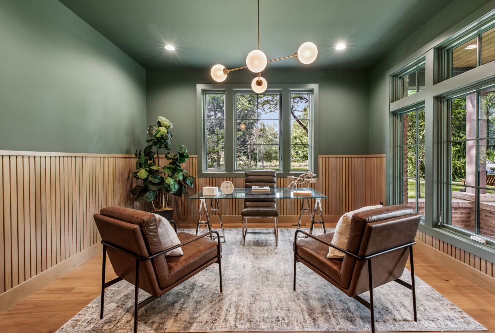 Klassisches Arbeitszimmer mit grüner Wandfarbe, braunem Holzboden, freistehendem Schreibtisch, braunem Boden und vertäfelten Wänden in Denver