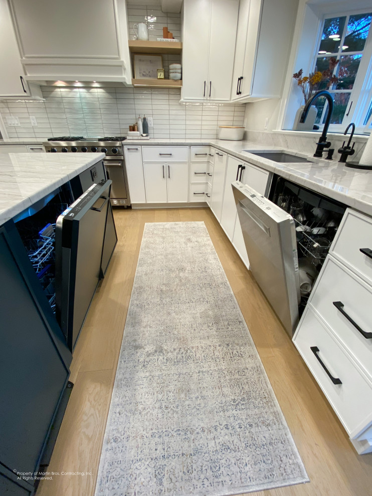 Inspiration for a large transitional u-shaped light wood floor open concept kitchen remodel with an undermount sink, flat-panel cabinets, white cabinets, quartzite countertops, white backsplash, porcelain backsplash, stainless steel appliances, an island and white countertops