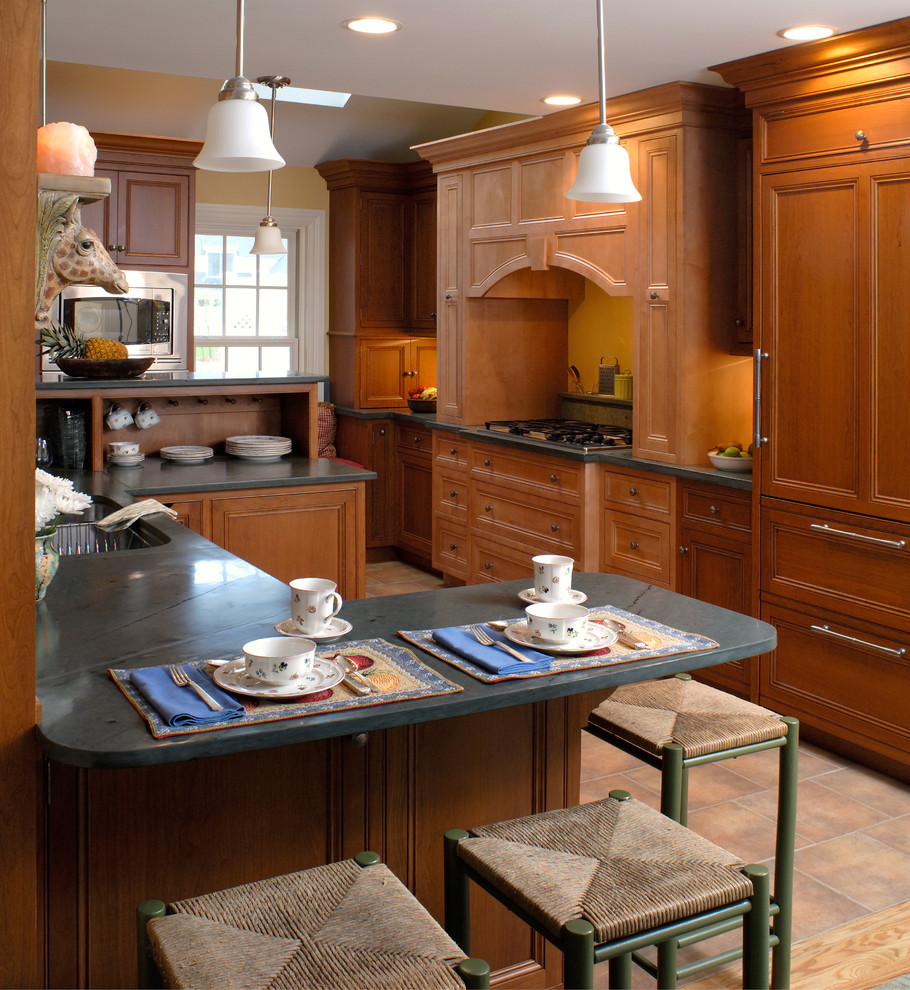 Design ideas for a large traditional u-shaped eat-in kitchen in Boston with recessed-panel cabinets, medium wood cabinets, soapstone benchtops, a peninsula, green splashback, stone slab splashback, stainless steel appliances, a double-bowl sink and ceramic floors.