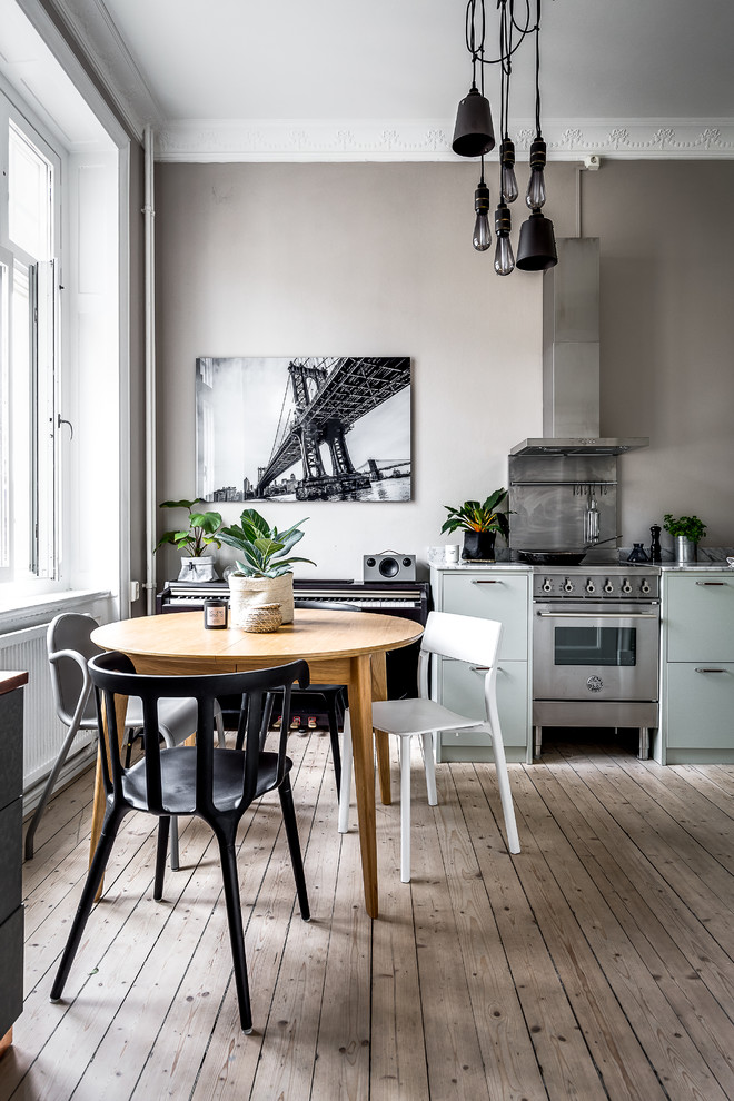 This is an example of a scandinavian kitchen/dining combo in Stockholm with grey walls, light hardwood floors and beige floor.