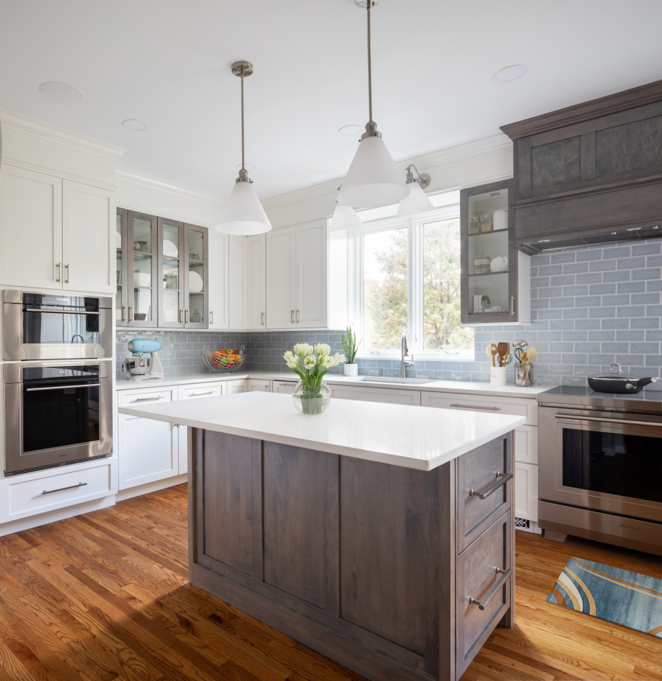 Enclosed kitchen - mid-sized transitional l-shaped medium tone wood floor and brown floor enclosed kitchen idea with an undermount sink, shaker cabinets, white cabinets, quartz countertops, blue backsplash, subway tile backsplash, stainless steel appliances, an island and white countertops