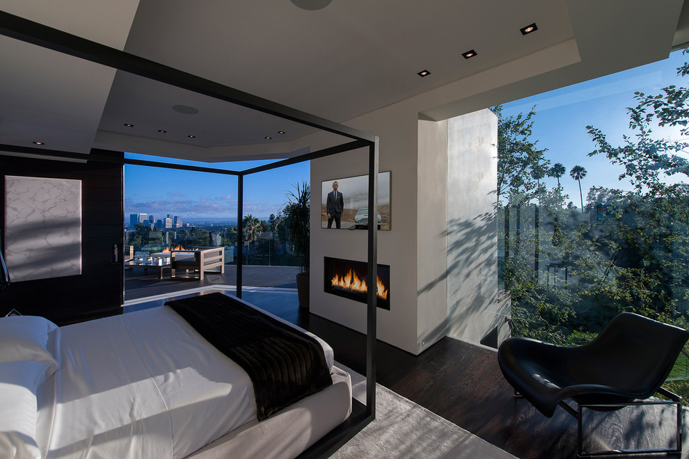 This is an example of an expansive modern guest bedroom in Los Angeles with multi-coloured walls, dark hardwood floors, a standard fireplace, brown floor and recessed.