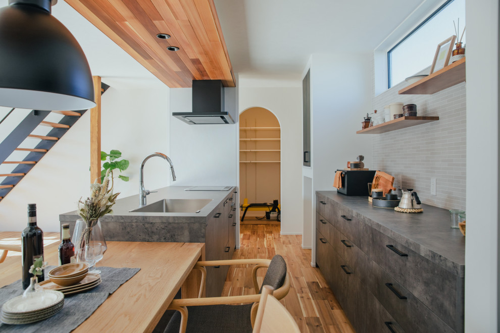 Offene, Einzeilige Moderne Küche mit schwarzen Schränken, braunem Holzboden, beigem Boden, schwarzer Arbeitsplatte und Holzdecke in Sonstige