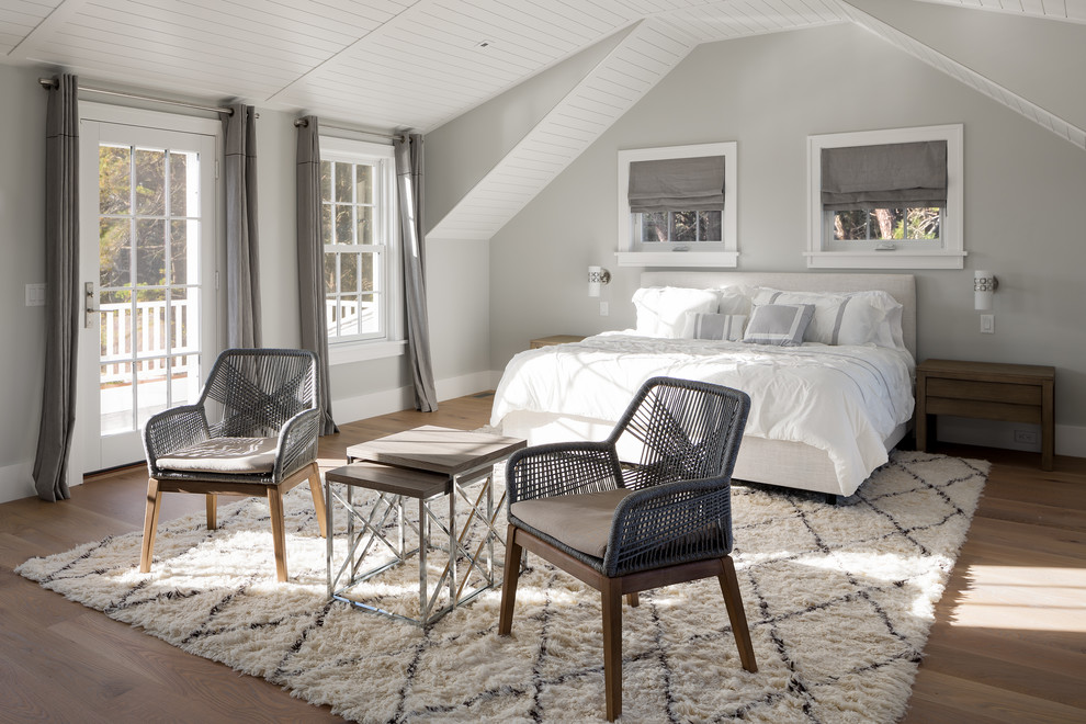 Inspiration for a large beach style master bedroom in Boston with grey walls, light hardwood floors, a hanging fireplace and a metal fireplace surround.
