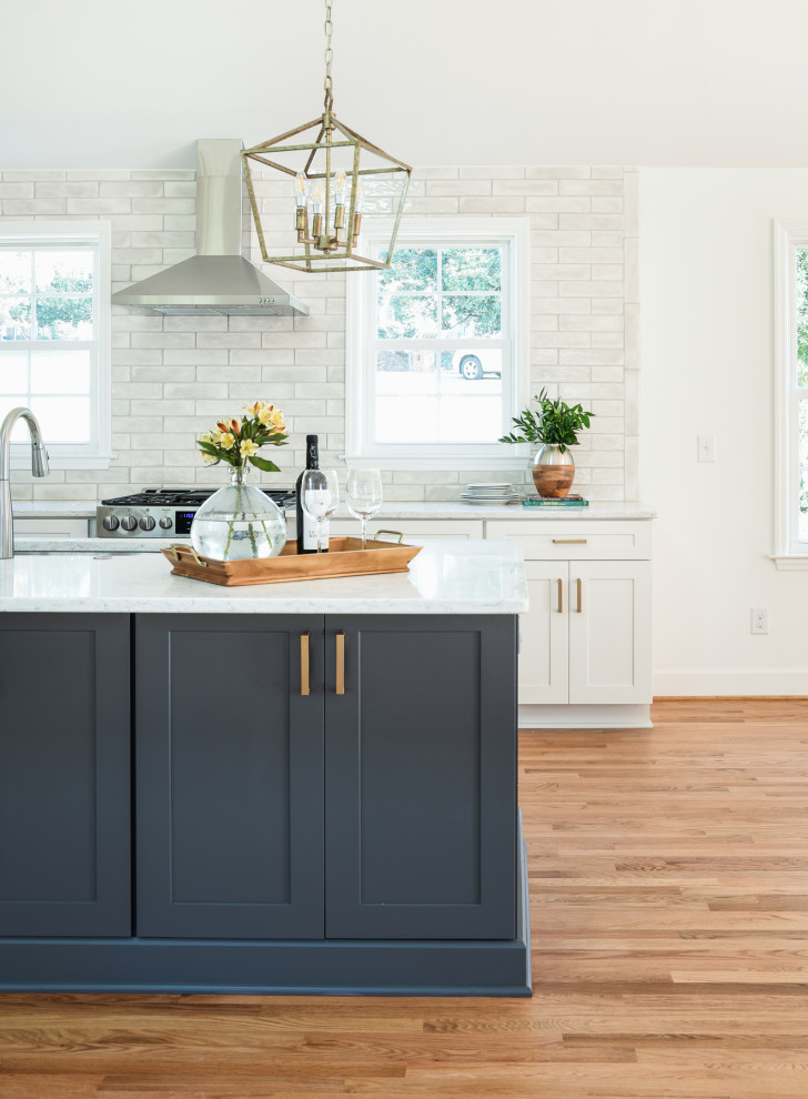 Inspiration for a large transitional light wood floor and brown floor eat-in kitchen remodel in Nashville with an undermount sink, shaker cabinets, white cabinets, quartz countertops, gray backsplash, subway tile backsplash, stainless steel appliances, an island and white countertops