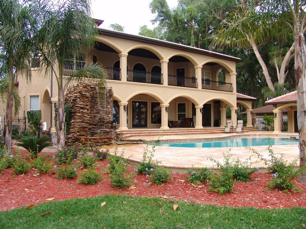 Large mediterranean backyard kidney-shaped lap pool in Jacksonville with tile and a pool house.