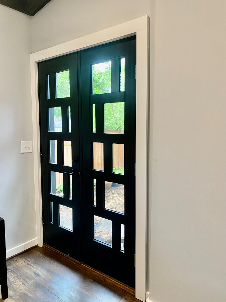 Photo of a mid-sized modern entryway in DC Metro with white walls, dark hardwood floors, a double front door, a black front door and exposed beam.