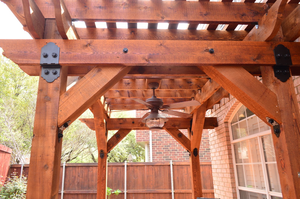 This is an example of a mid-sized country side yard patio in Dallas with stamped concrete and a pergola.