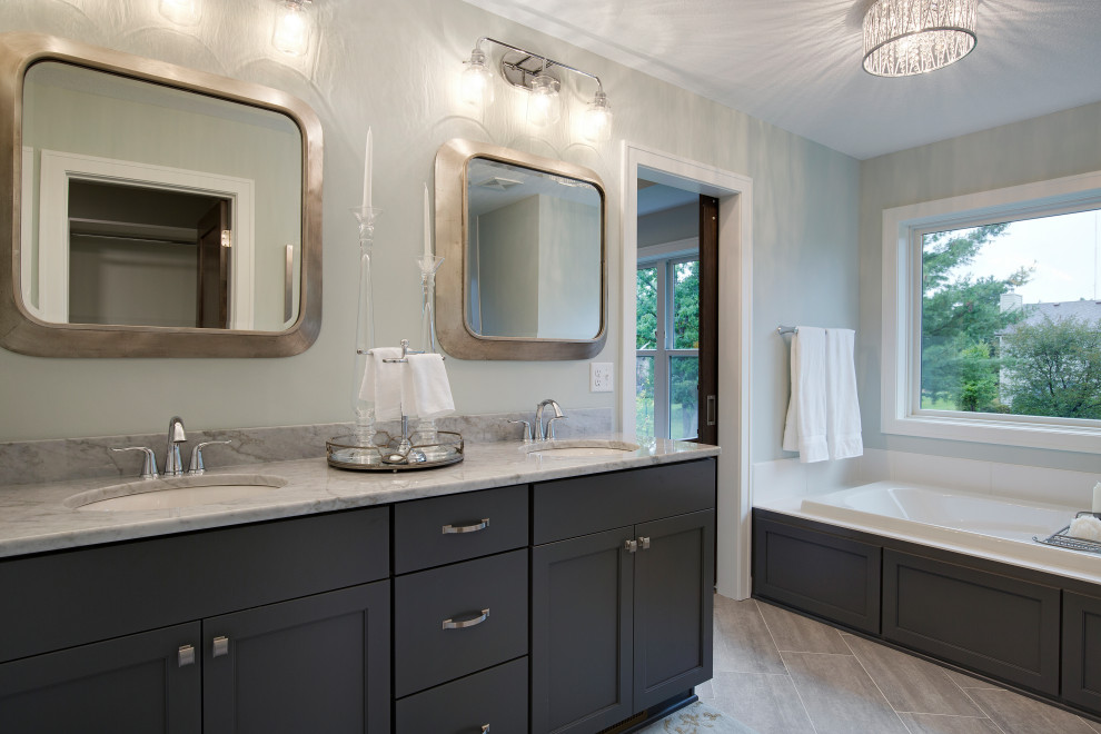 Large transitional master bathroom in Minneapolis with flat-panel cabinets, black cabinets, a drop-in tub, gray tile, grey walls, ceramic floors, an undermount sink, granite benchtops, grey floor and grey benchtops.