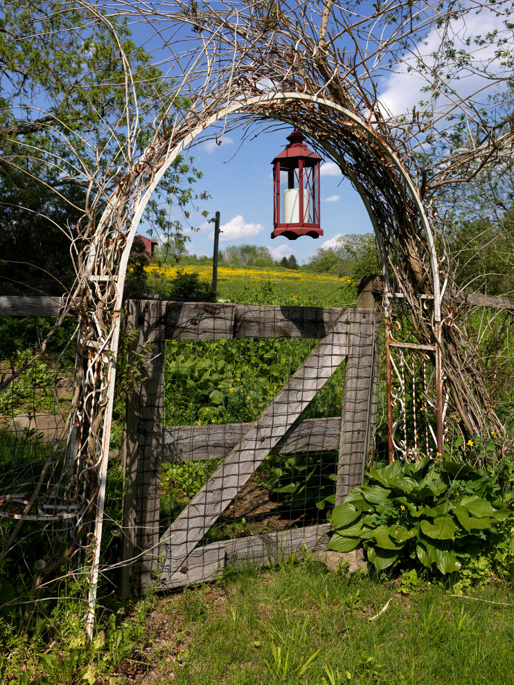 Foto di un grande giardino country esposto in pieno sole dietro casa in estate con recinzione in legno