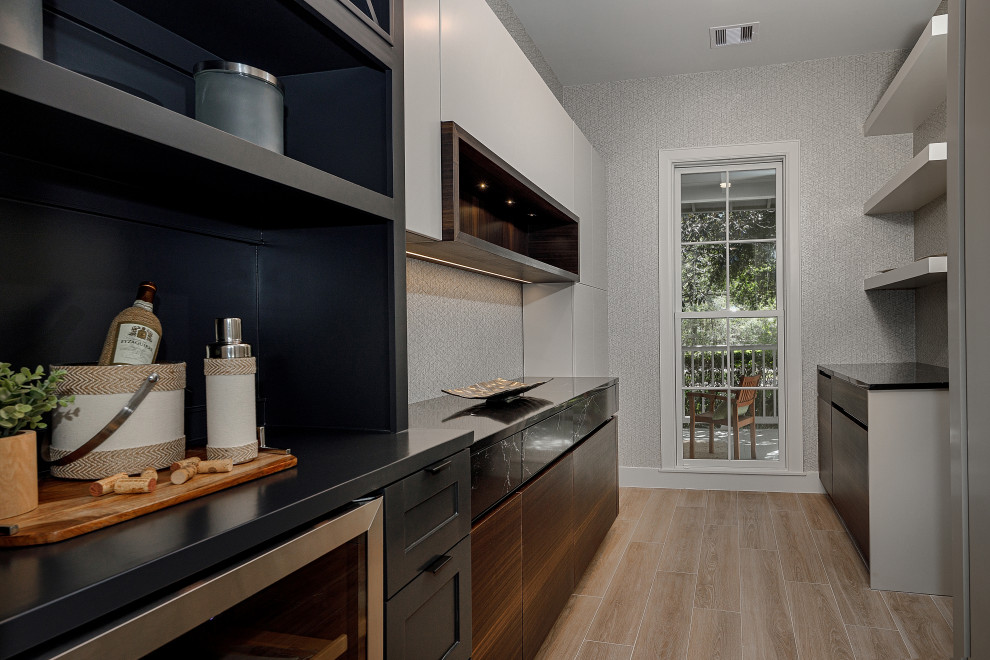 This is an example of a medium sized contemporary galley dry bar in Houston with no sink, flat-panel cabinets, beige floors, black worktops, dark wood cabinets, engineered stone countertops and porcelain flooring.