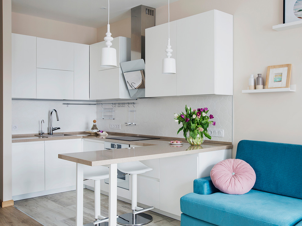 This is an example of a scandinavian u-shaped open plan kitchen in Moscow with a drop-in sink, flat-panel cabinets, white cabinets, white splashback, white appliances and no island.
