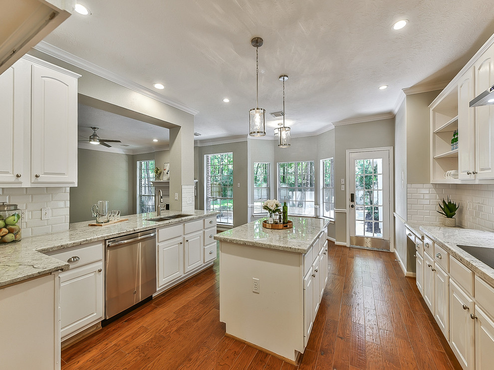 This is an example of a mid-sized transitional u-shaped eat-in kitchen in Houston with an undermount sink, louvered cabinets, white cabinets, granite benchtops, white splashback, subway tile splashback, stainless steel appliances, medium hardwood floors, with island, orange floor and white benchtop.