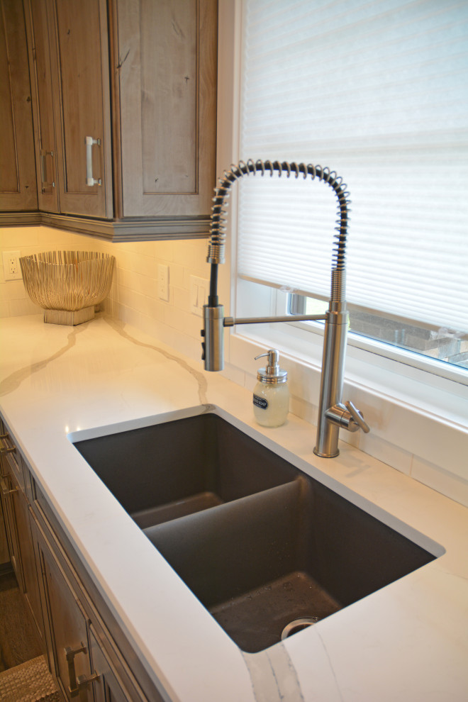 Inspiration for a small transitional u-shaped brown floor eat-in kitchen remodel with an undermount sink, recessed-panel cabinets, medium tone wood cabinets, quartz countertops, white backsplash, subway tile backsplash, stainless steel appliances, a peninsula and white countertops