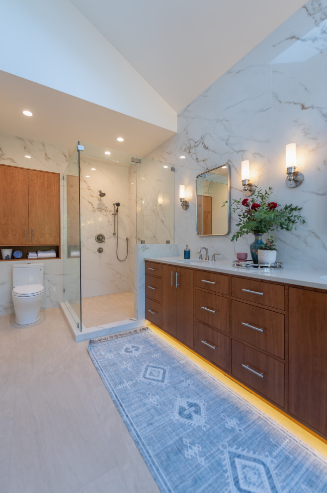 This is an example of a mid-sized contemporary master bathroom in Portland with flat-panel cabinets, medium wood cabinets, a freestanding tub, an open shower, white tile, porcelain tile, white walls, porcelain floors, an undermount sink, engineered quartz benchtops, grey floor, white benchtops, a shower seat, a double vanity, a built-in vanity, vaulted and an open shower.
