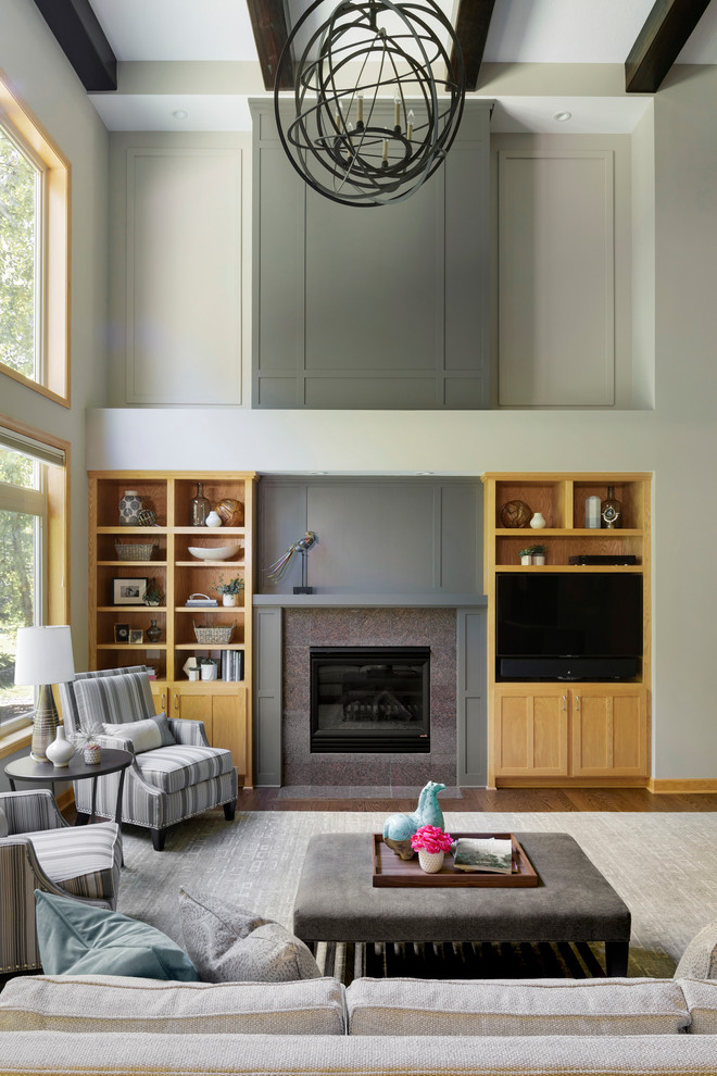 This is an example of an expansive transitional open concept living room in Minneapolis with grey walls, dark hardwood floors, a standard fireplace, brown floor, a freestanding tv and a stone fireplace surround.
