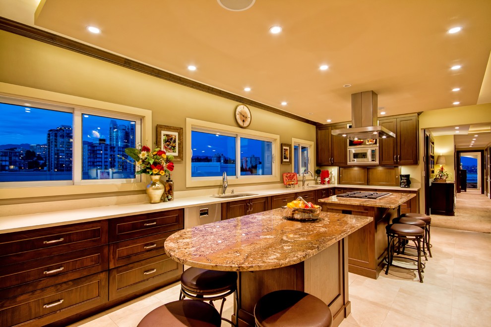 Large transitional kitchen in Vancouver with an undermount sink, shaker cabinets, dark wood cabinets, granite benchtops, stainless steel appliances, porcelain floors and multiple islands.