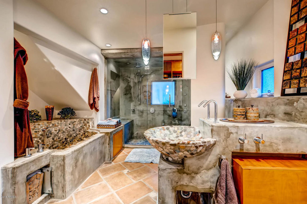 Mid-sized master bathroom in Phoenix with an alcove tub, an alcove shower, a two-piece toilet, gray tile, pebble tile, beige walls, terra-cotta floors, a vessel sink, concrete benchtops, brown floor, a hinged shower door and grey benchtops.