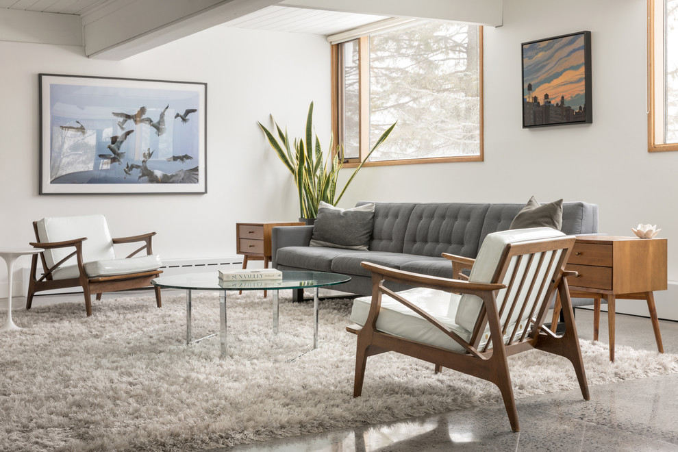 Inspiration for a midcentury living room in Portland Maine with white walls and grey floor.