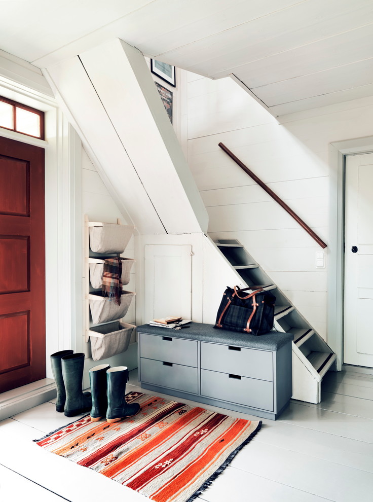 Photo of a country foyer in Malmo with white walls, painted wood floors, a single front door and a red front door.