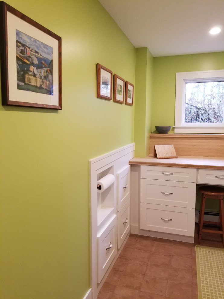 Mid-sized transitional l-shaped dedicated laundry room in Other with an utility sink, white cabinets, wood benchtops, green walls, porcelain floors, a side-by-side washer and dryer, brown floor, brown benchtop and shaker cabinets.