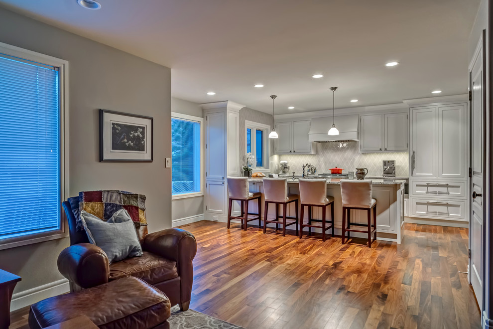 Example of a mid-sized transitional u-shaped medium tone wood floor open concept kitchen design in Calgary with an undermount sink, recessed-panel cabinets, gray cabinets, granite countertops, gray backsplash, glass tile backsplash, stainless steel appliances and an island
