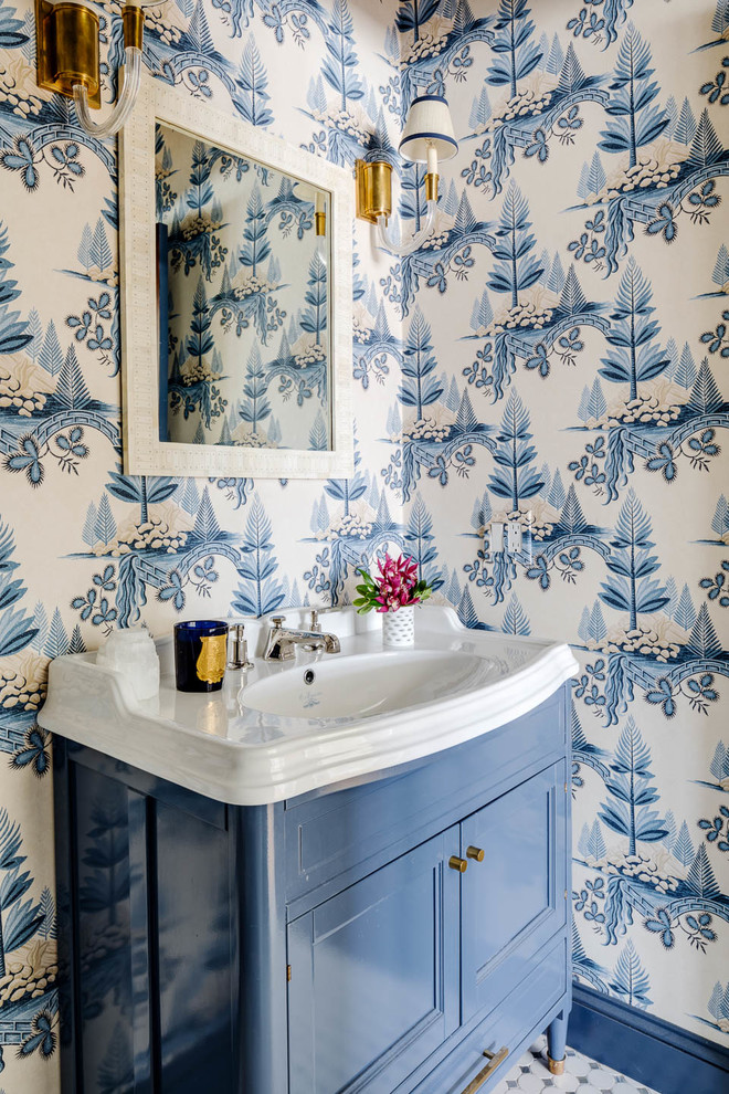 This is an example of a beach style powder room in Providence with furniture-like cabinets, blue cabinets, multi-coloured walls, an integrated sink, multi-coloured floor and white benchtops.