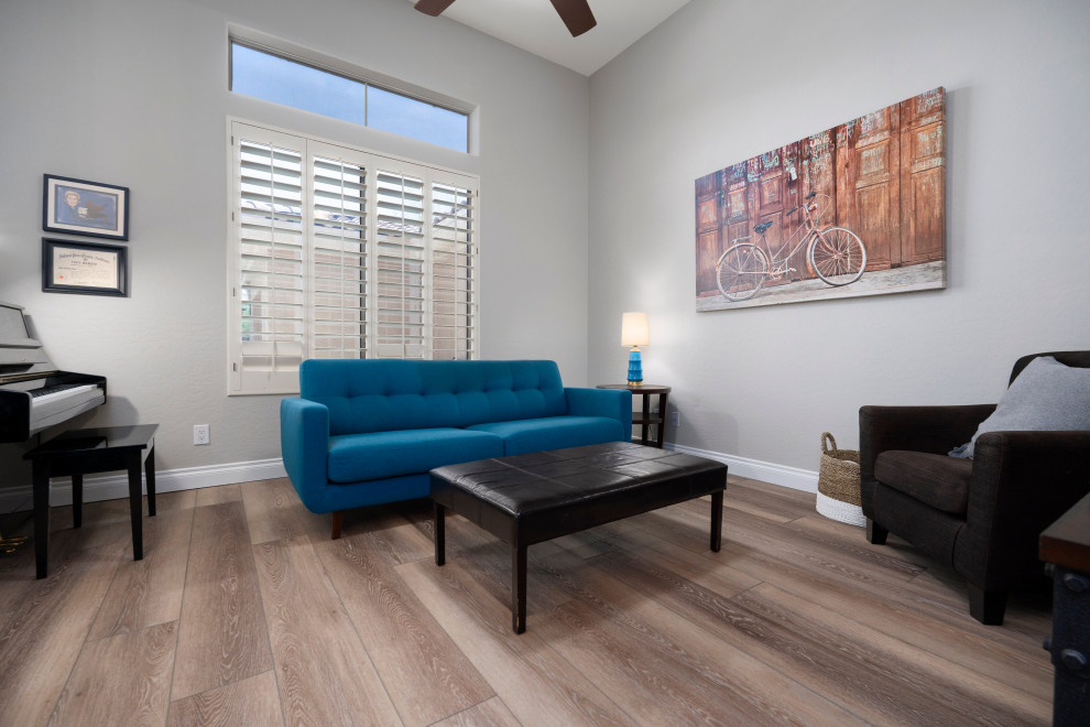 This is an example of a large modern formal enclosed living room in Phoenix with grey walls, vinyl flooring, a freestanding tv and brown floors.