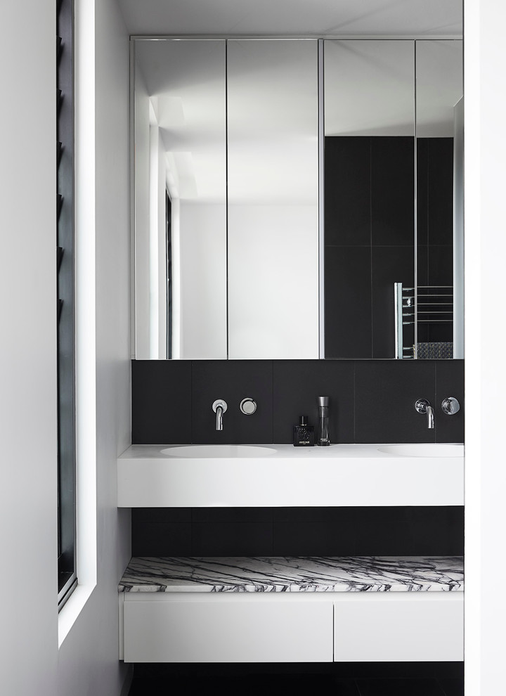 Photo of a mid-sized contemporary master bathroom in Melbourne with white cabinets, black tile, porcelain tile, white walls, porcelain floors, marble benchtops, flat-panel cabinets and an integrated sink.