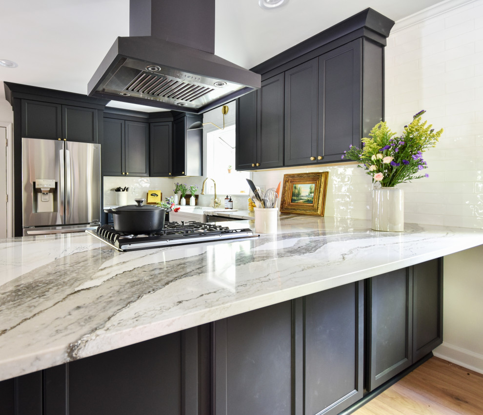 Inspiration for a mid-sized transitional u-shaped laminate floor open concept kitchen remodel with a farmhouse sink, black cabinets, quartzite countertops, white backsplash and a peninsula