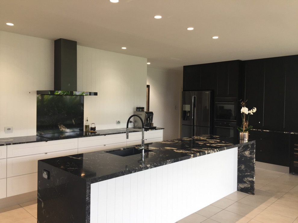 Large modern kitchen pantry in Sunshine Coast with an undermount sink, shaker cabinets, black cabinets, granite benchtops, granite splashback, black appliances and with island.