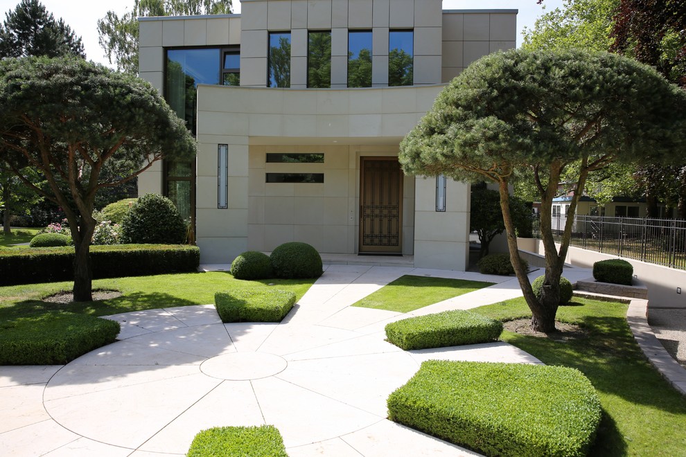 Design ideas for a large contemporary front yard patio in Frankfurt with natural stone pavers.