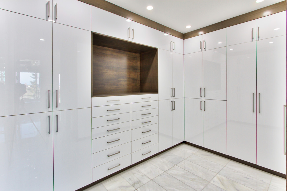 This is an example of an expansive modern gender-neutral walk-in wardrobe in Calgary with flat-panel cabinets, medium wood cabinets and marble floors.