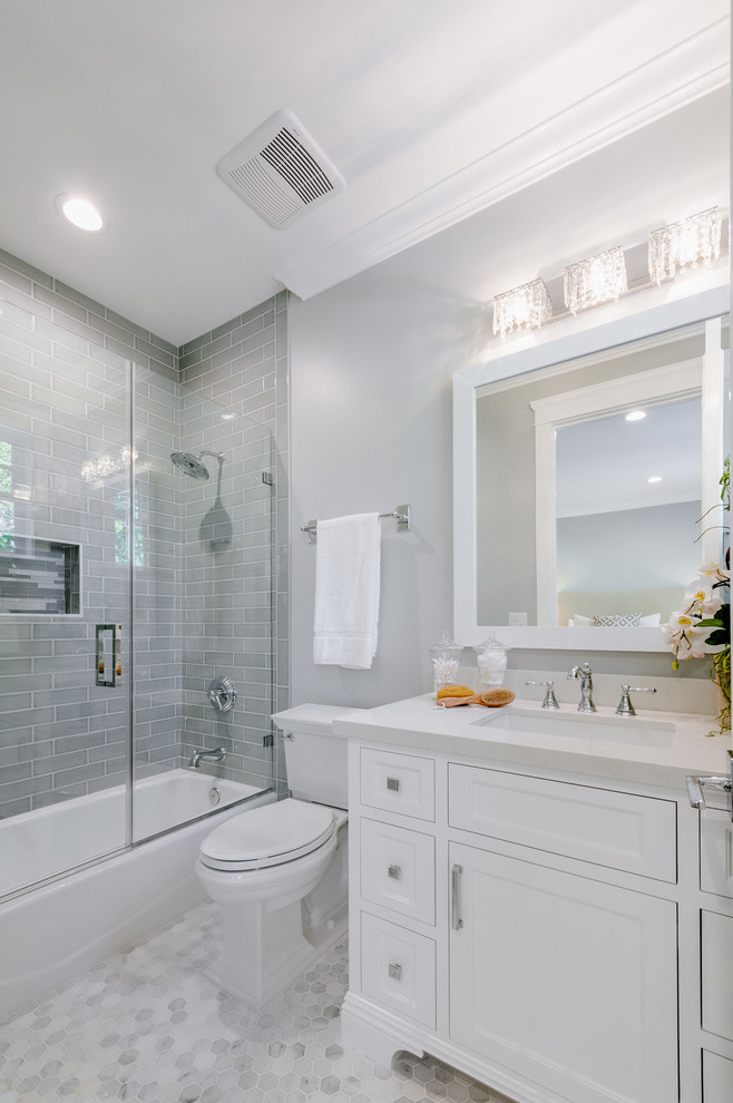 This is an example of a small transitional bathroom in Los Angeles with beaded inset cabinets, white cabinets, an alcove tub, a shower/bathtub combo, a two-piece toilet, grey walls, an undermount sink, quartzite benchtops and a hinged shower door.