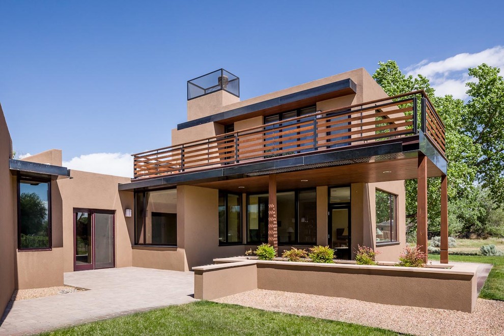 This is an example of a large two-storey stucco beige house exterior in Albuquerque with a flat roof and a metal roof.