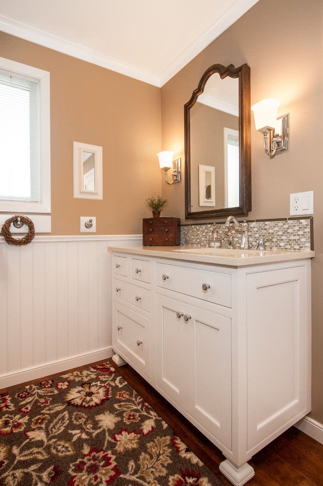 This is an example of a mid-sized traditional bathroom in Boise with an undermount sink, furniture-like cabinets, white cabinets, engineered quartz benchtops, beige tile, mosaic tile, brown walls and medium hardwood floors.