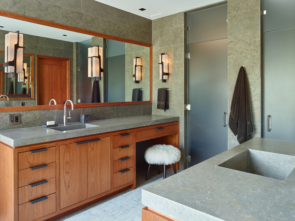 Design ideas for a large contemporary master bathroom in Portland with flat-panel cabinets, medium wood cabinets, gray tile, grey walls, an integrated sink, a double shower, limestone floors, limestone benchtops, a hinged shower door and limestone.
