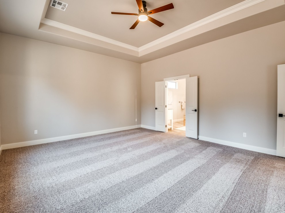 This is an example of a large country master bedroom in Oklahoma City with beige walls, carpet and beige floor.