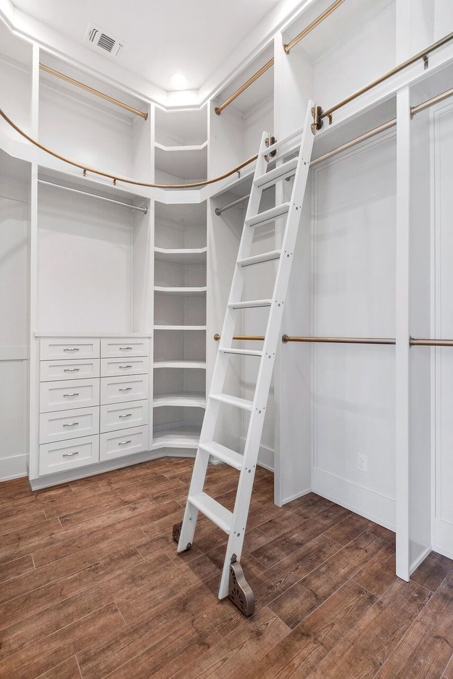 This is an example of a transitional gender-neutral walk-in wardrobe in New Orleans with shaker cabinets, white cabinets, medium hardwood floors and beige floor.