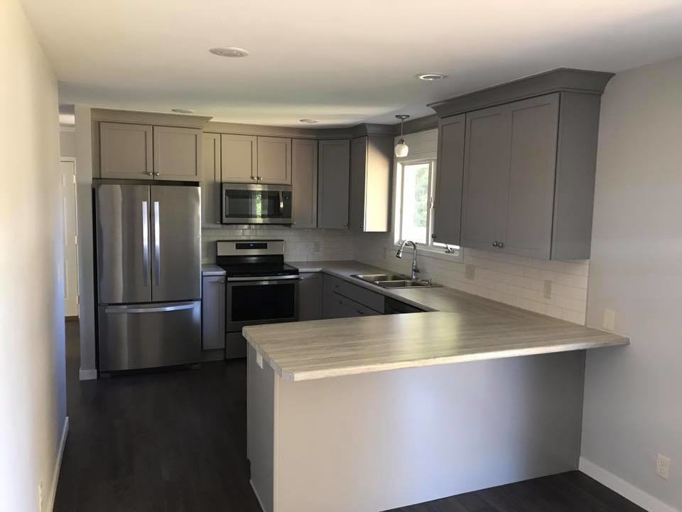 Inspiration for a mid-sized transitional u-shaped vinyl floor and brown floor kitchen remodel with a drop-in sink, shaker cabinets, gray cabinets, laminate countertops, white backsplash, subway tile backsplash, stainless steel appliances, a peninsula and gray countertops