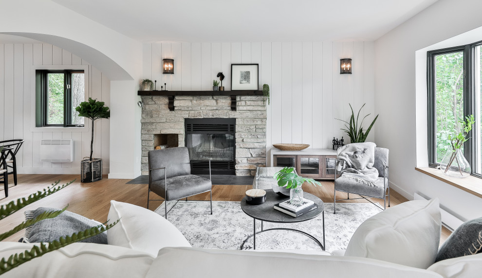 Mid-sized scandinavian living room in Montreal with white walls, light hardwood floors, a wood stove, a stone fireplace surround and planked wall panelling.