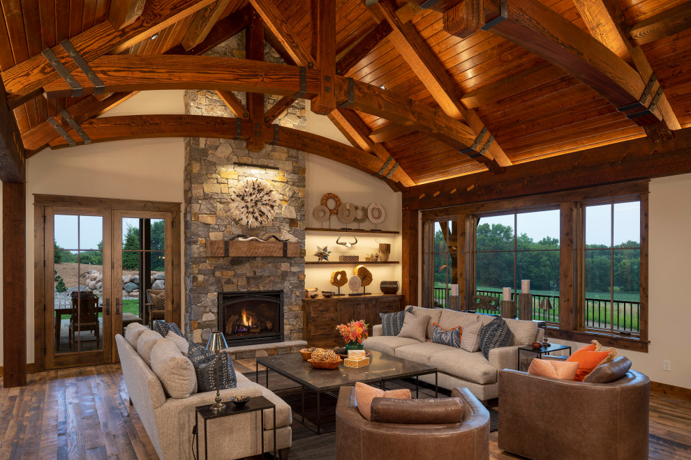 This is an example of an expansive country open concept family room in Minneapolis with grey walls, medium hardwood floors, a standard fireplace, no tv, multi-coloured floor, exposed beam and planked wall panelling.