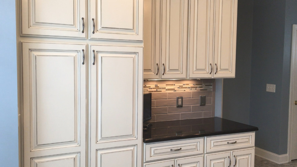 Kitchen - mid-sized vinyl floor kitchen idea with an undermount sink, raised-panel cabinets, distressed cabinets, ceramic backsplash, stainless steel appliances and an island