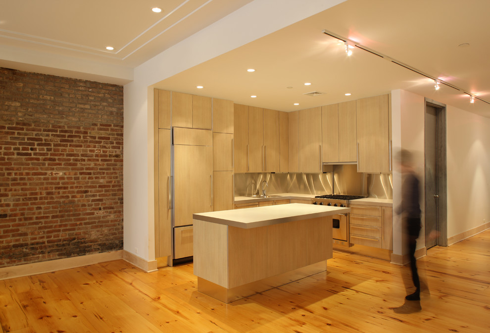 Photo of a small industrial l-shaped open plan kitchen in New York with a drop-in sink, flat-panel cabinets, light wood cabinets, concrete benchtops, panelled appliances, light hardwood floors, with island, beige floor and grey benchtop.