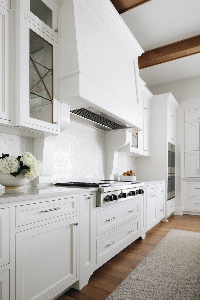 Bild på ett stort vintage vit vitt kök och matrum, med en undermonterad diskho, luckor med profilerade fronter, vita skåp, bänkskiva i kvarts, stänkskydd i stenkakel, integrerade vitvaror, ljust trägolv, flera köksöar och brunt golv